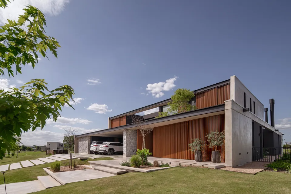Modern two-storey house with timber slat cladding and grey walls behind a lawn crossed by stepping-stone paths.