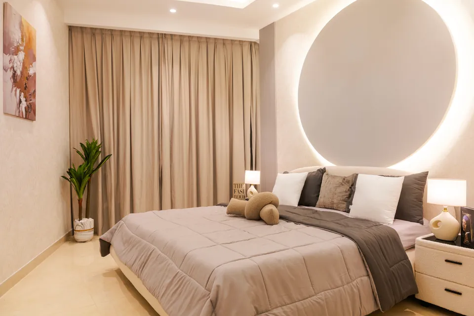 Imperial Avenue Apartment, Downtown Dubai: bedroom with a backlit circular wall feature, grey bedding and beige curtains.