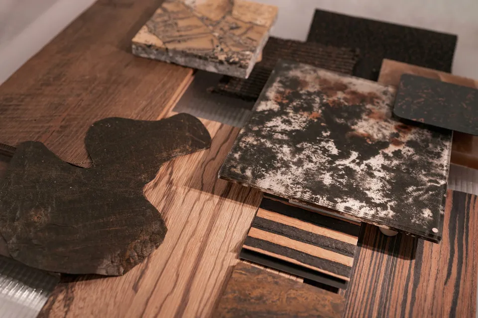Close-up of layered material samples in wood grain, dark stone-look and textured finishes on a timber surface.