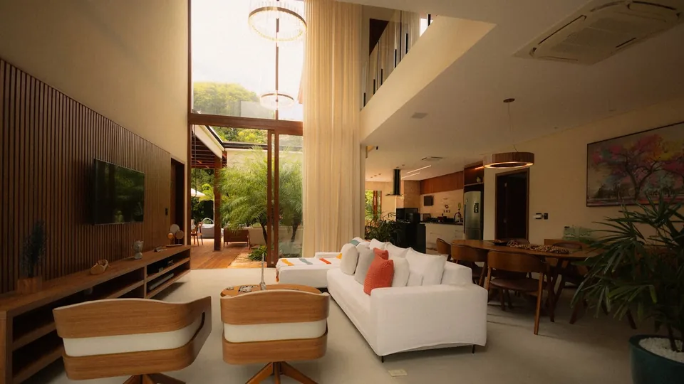 Open-plan living and dining room with a white sofa, curved wooden swivel chairs and a slatted wood TV wall.