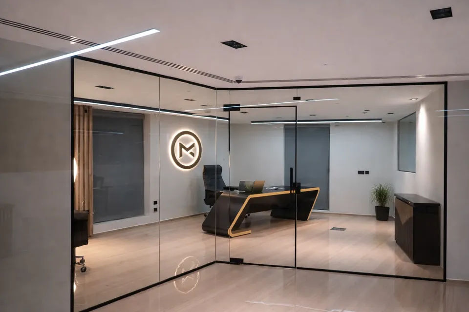 MK Pay, Al Rigga: glass-walled private office with a black and gold desk and a backlit circular logo.